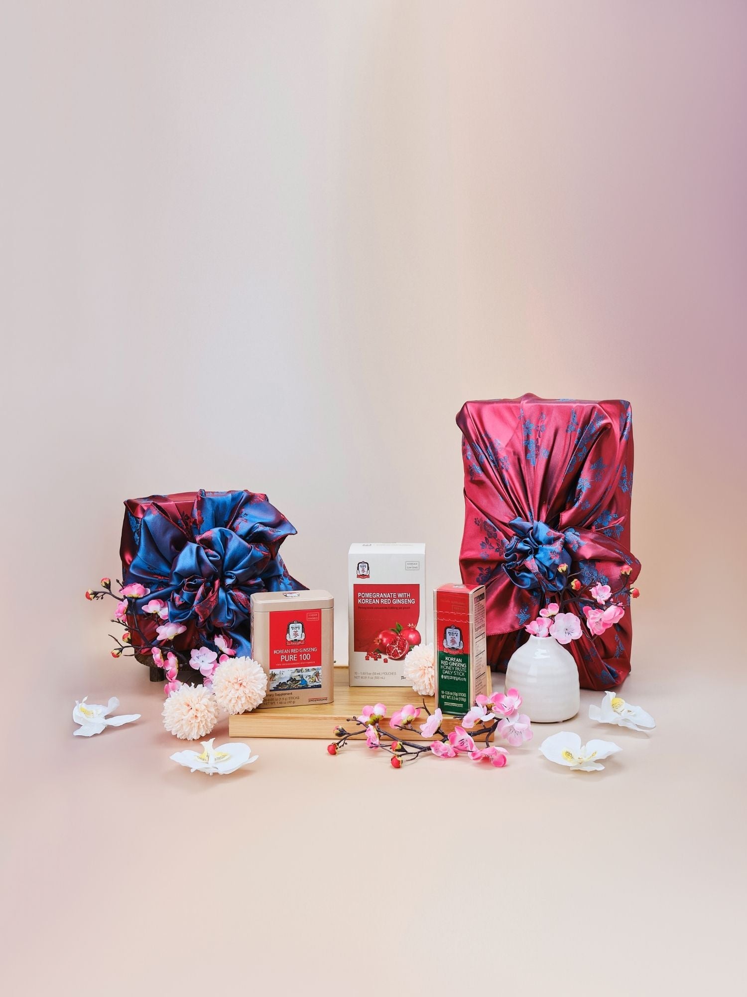 Lunar New Year Vitality Gift Set featuring pomegranate with Korean red ginseng, Pure 100 extract, and honey paste daily sticks displayed with a teapot, lantern and flowers